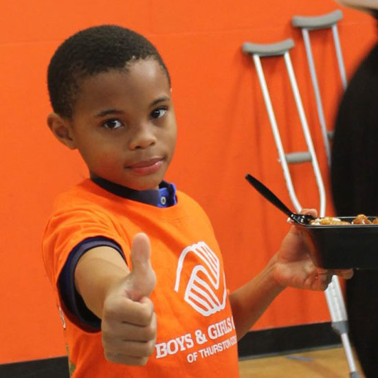 boy with orange t-shirt giving thumbs up